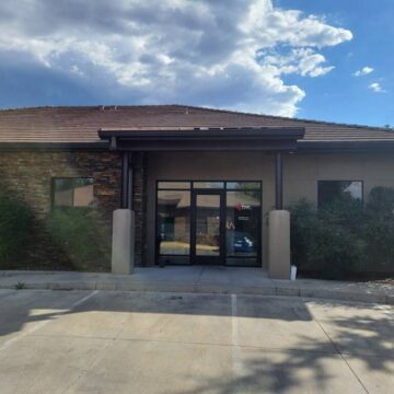Modern commercial building with accessible entrance and sustainable landscaping on a sunny day.