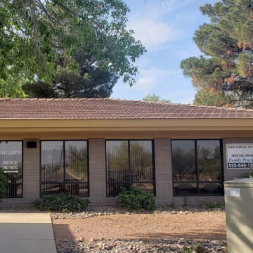 Suburban one-story commercial building with reflective windows and serene landscaping.