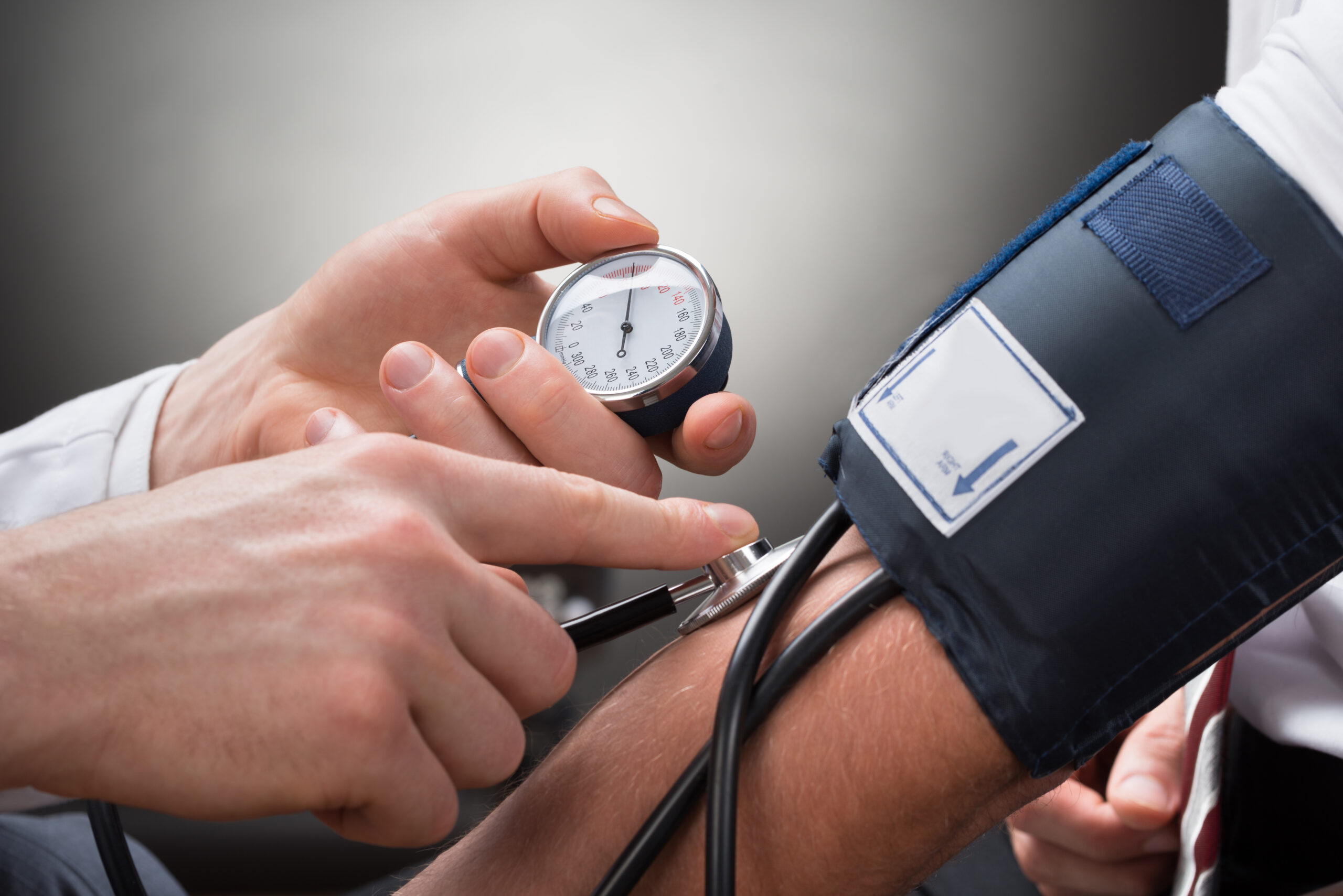 Doctor in white coat checks patients blood pressure with sphygmomanometer for heart health.
