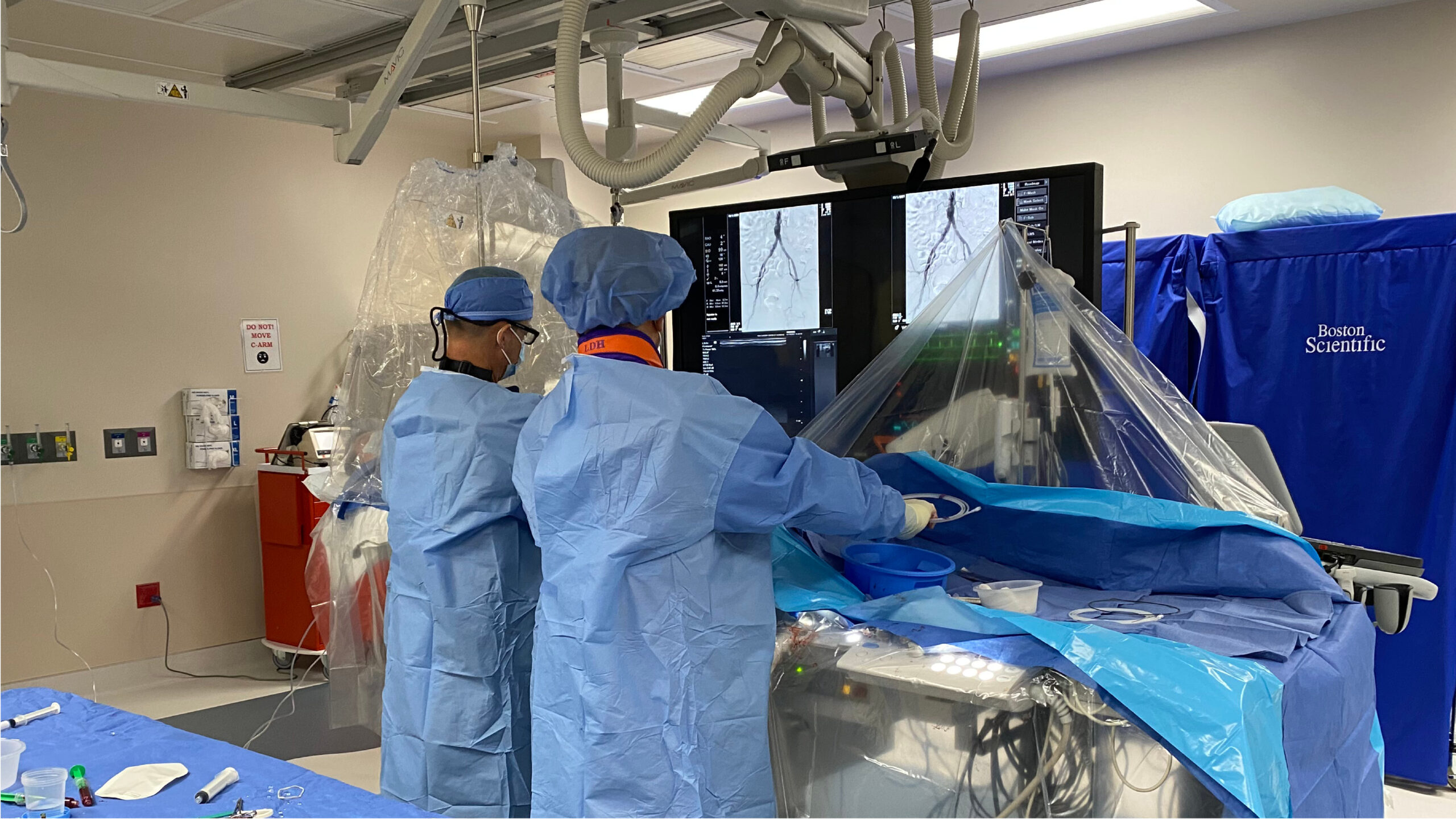 Two surgeons perform interventional surgery with advanced imaging, using Boston Scientific equipment.