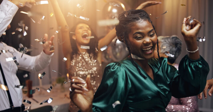 Elegant New Years gala with joyful dancing, diverse attendees, shimmering confetti, and ambient lighting.